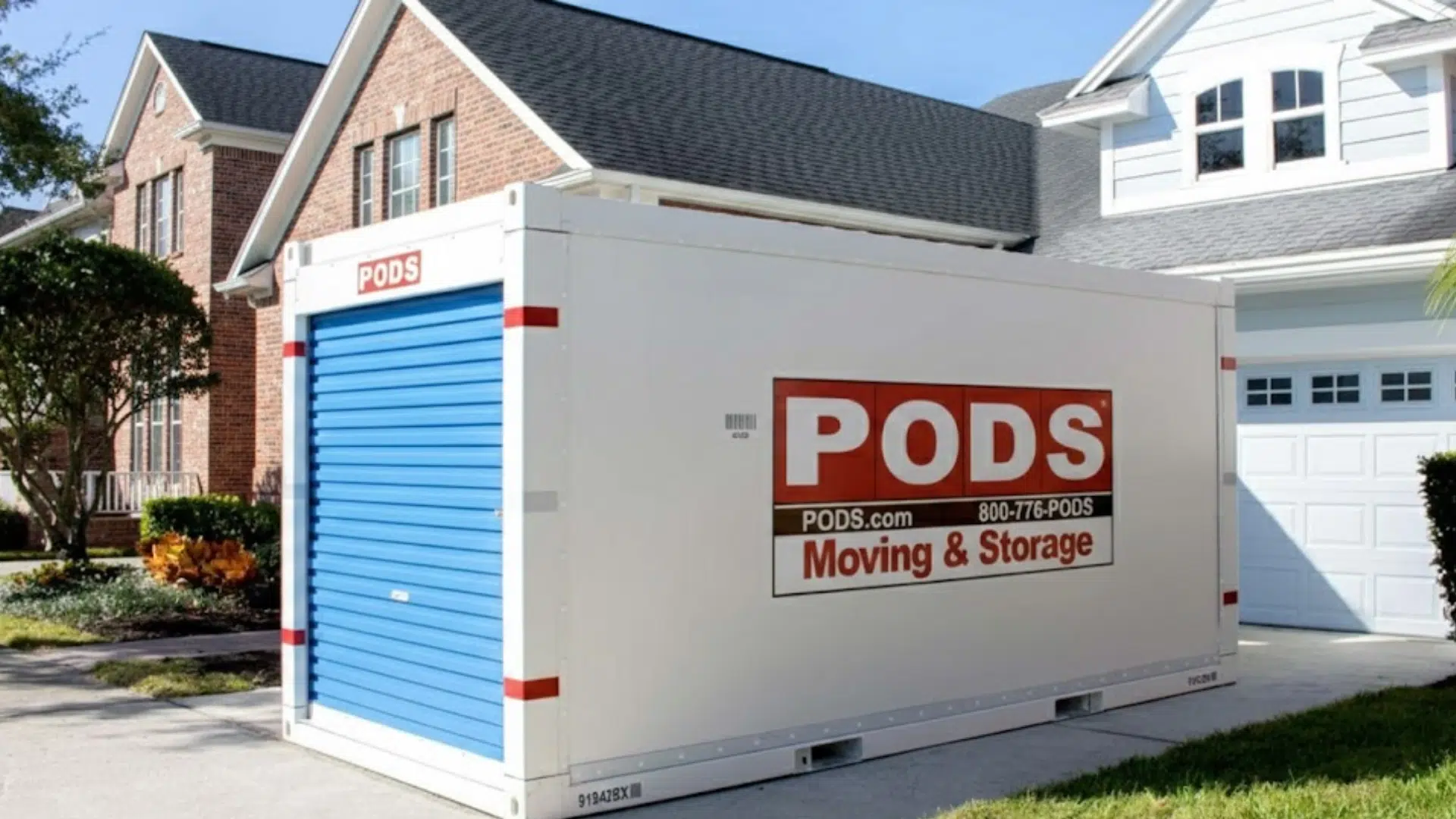 a white pods storage container sits in a residential driveway outside a suburban home with a garage, lawn, and trees