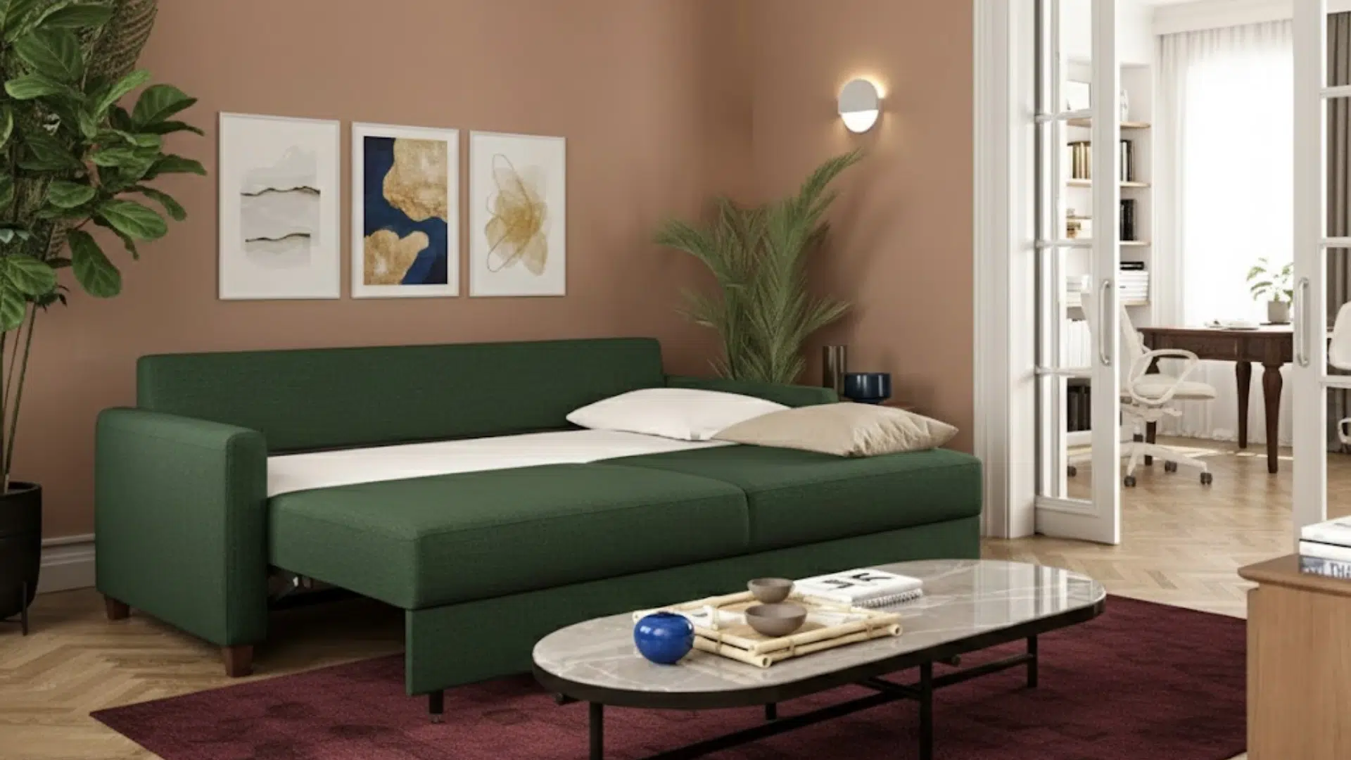 green sleeper sofa opened into a bed in a modern living room with coffee table, wall art, plants, and a home office in the background