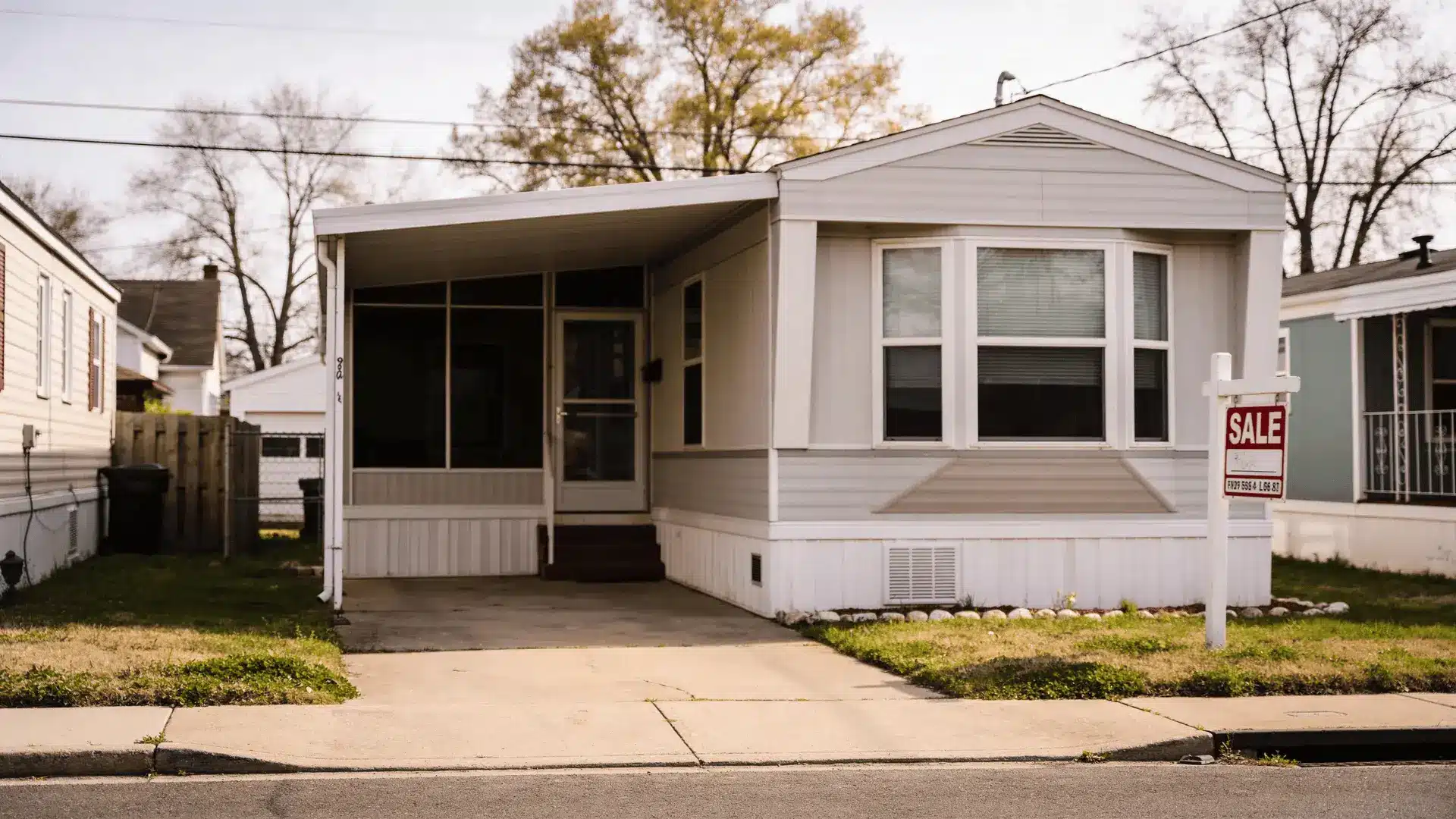 Modular home with a for sale sign in front yard on a quiet street