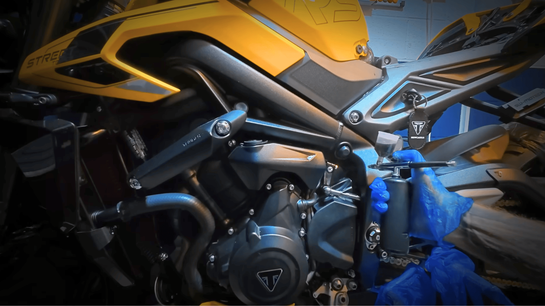 close-up of motorcycle engine being sprayed with rust cleaner during winter prep to protect parts from corrosion