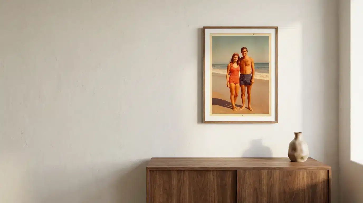 Framed beach photo on beige wall above wooden cabinet with ceramic vase