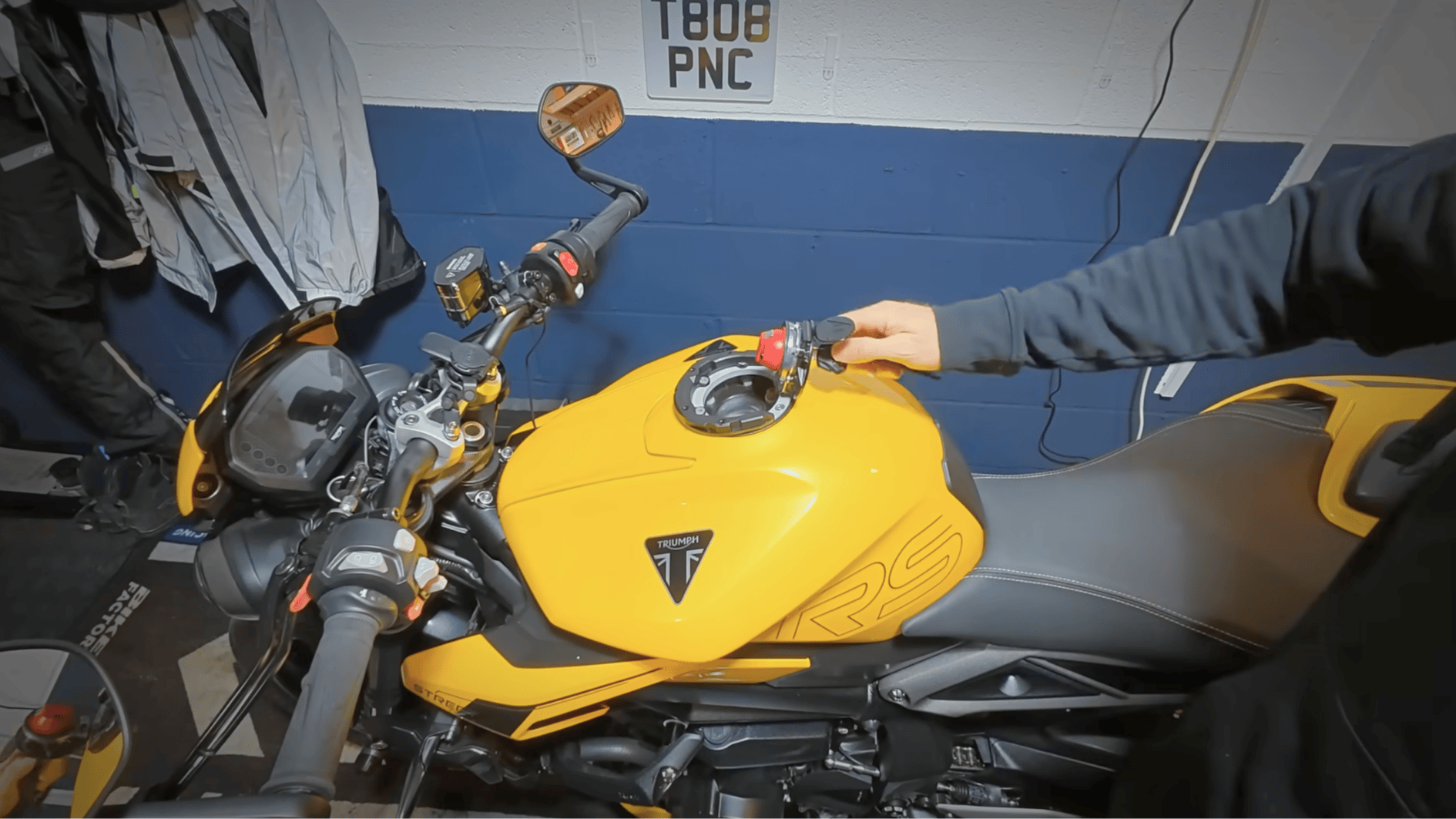 hand removing motorcycle fuel cap to add fuel stabilizer before storing bike for winter months in garage