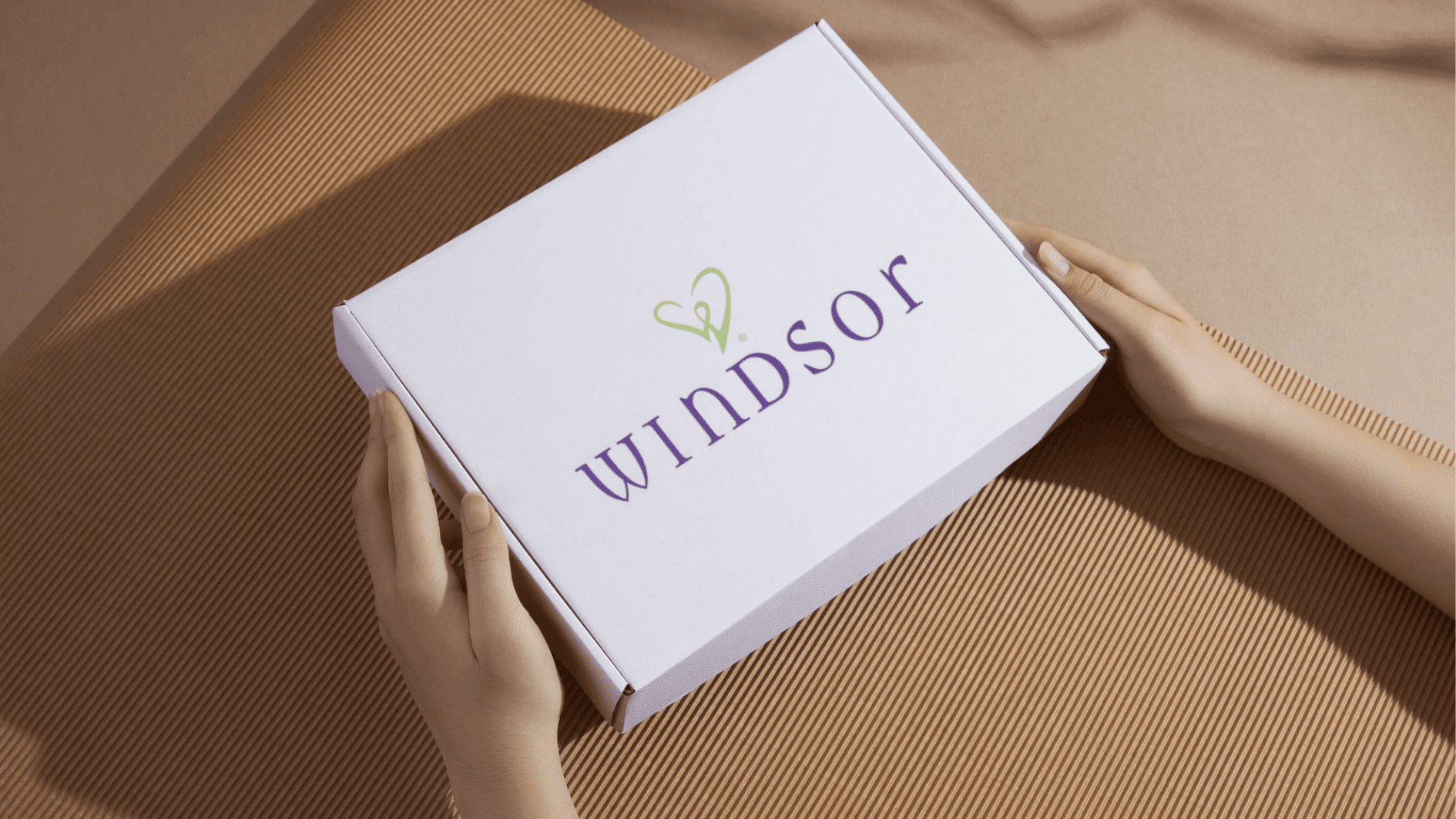 hands holding branded Windsor package box on table, showcasing product delivery, unboxing experience and packaging quality
