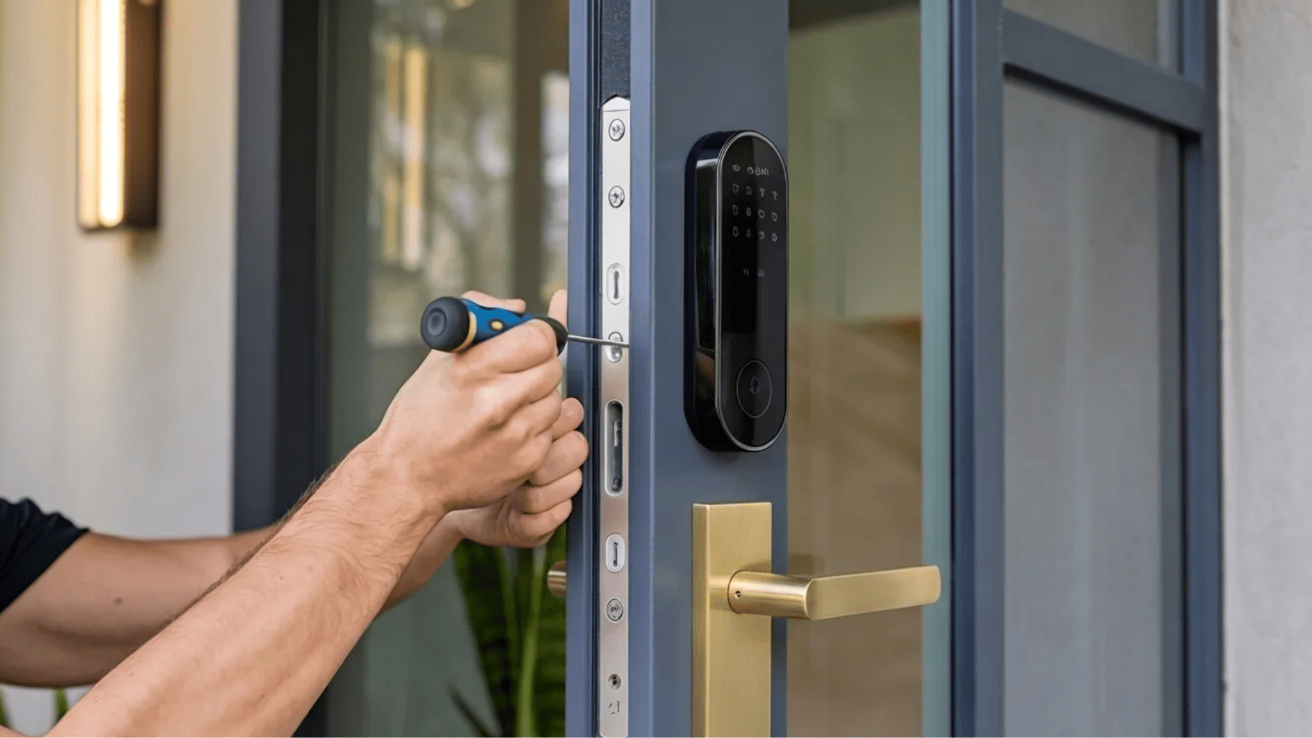 installing a smart door lock with a screwdriver on a modern door featuring a keypad lock and brass handle