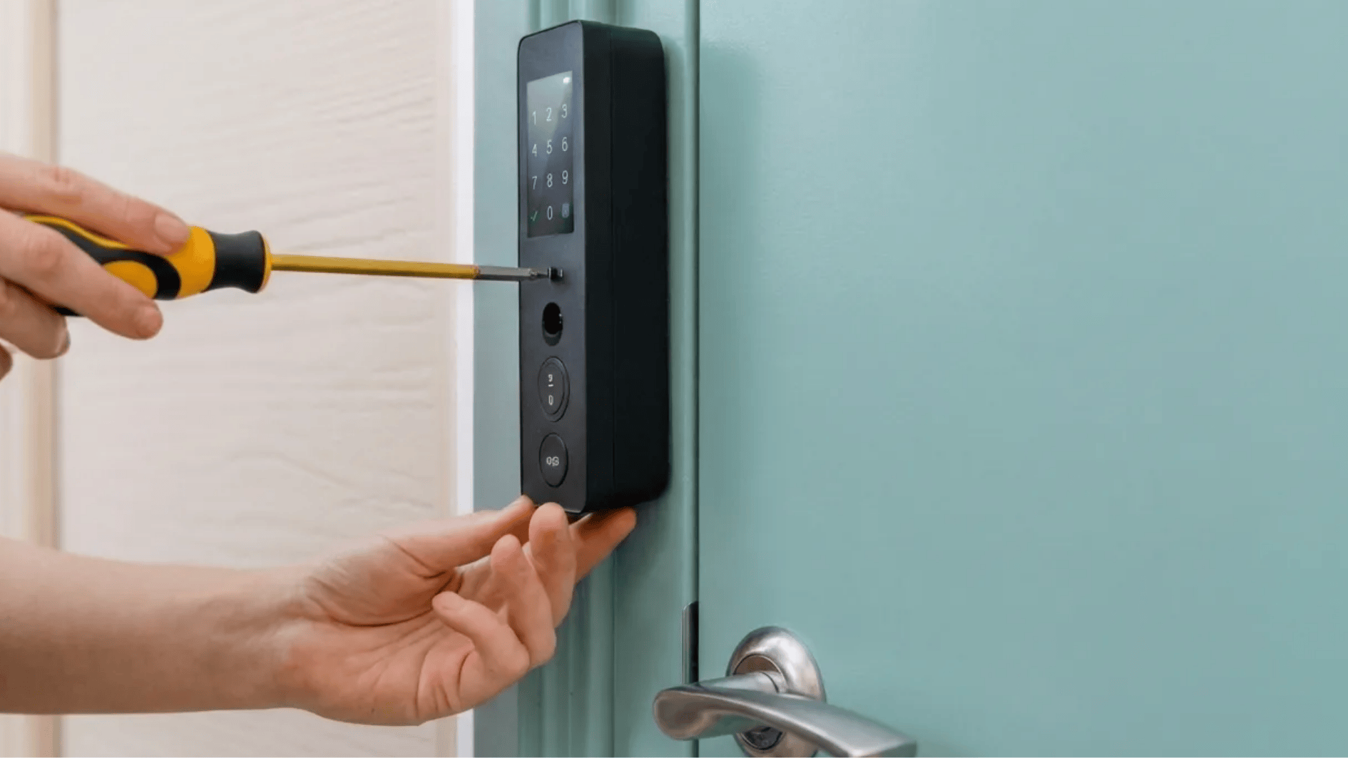 person installing a smart keypad door lock using a screwdriver on a teal door with a silver handle