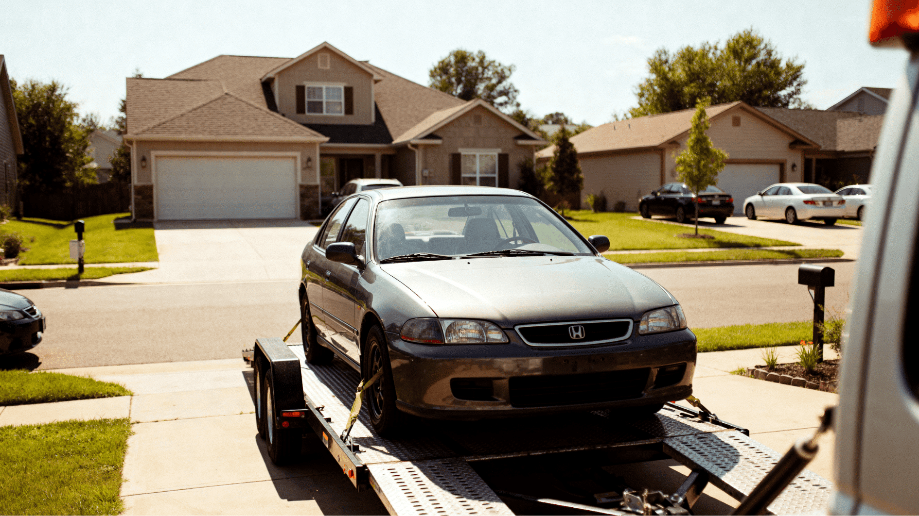 sedan secured on car trailer in suburban driveway, ready for vehicle transport and delivery service