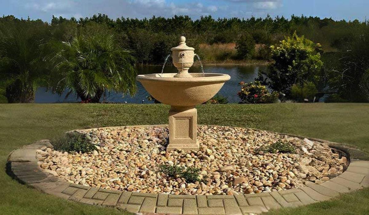 Tiered stone fountain in a garden with river rock base