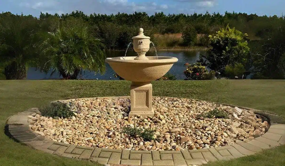 Tiered stone fountain in a garden with river rock base