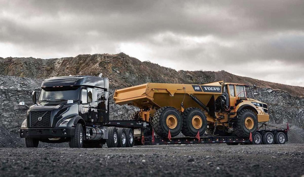 Black semi truck transporting a yellow Volvo dump truck