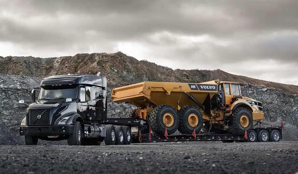Black semi truck transporting a yellow Volvo dump truck