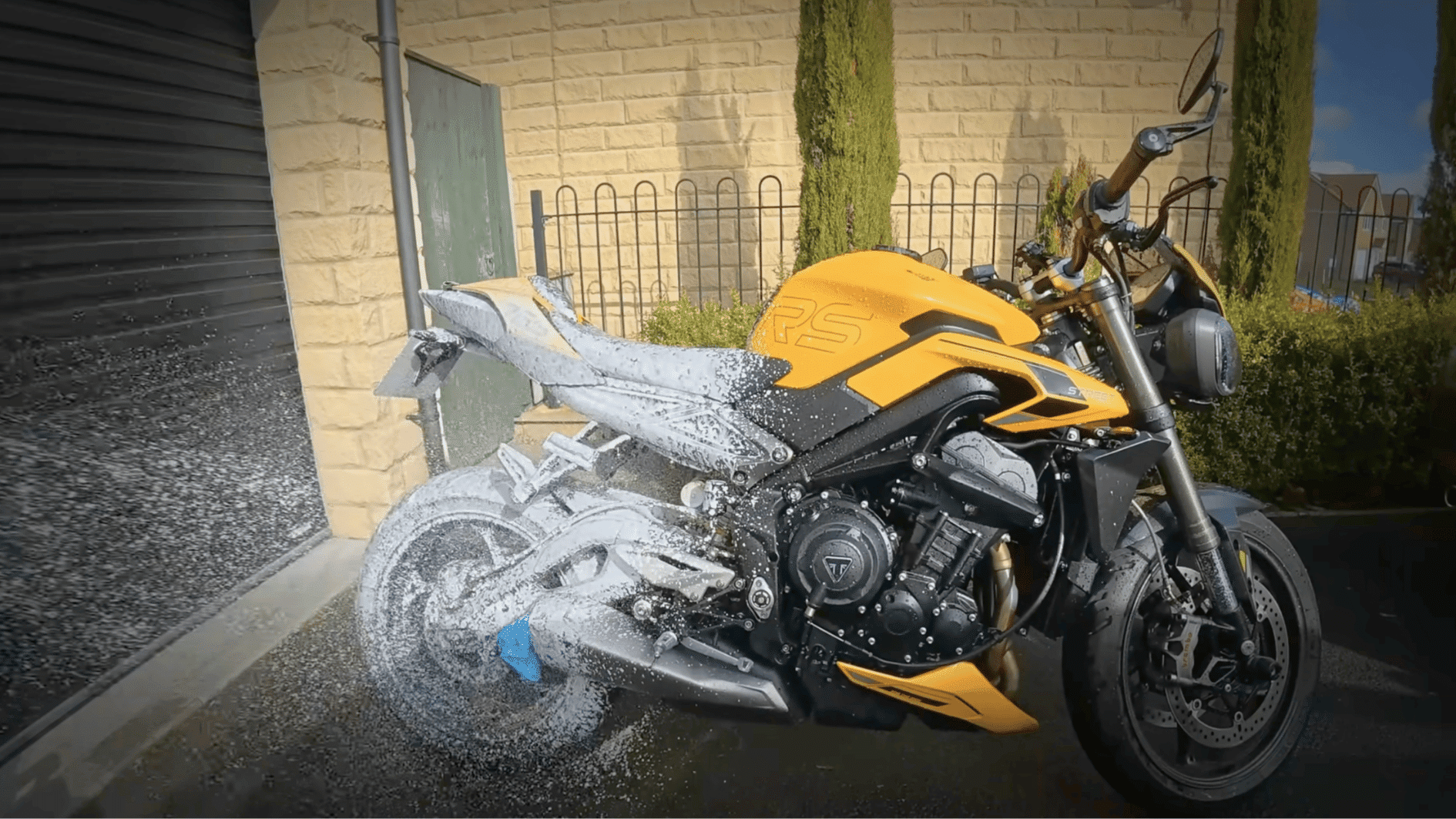 yellow motorcycle being washed with foam before winter storage to remove dirt, grime, and road salt buildup