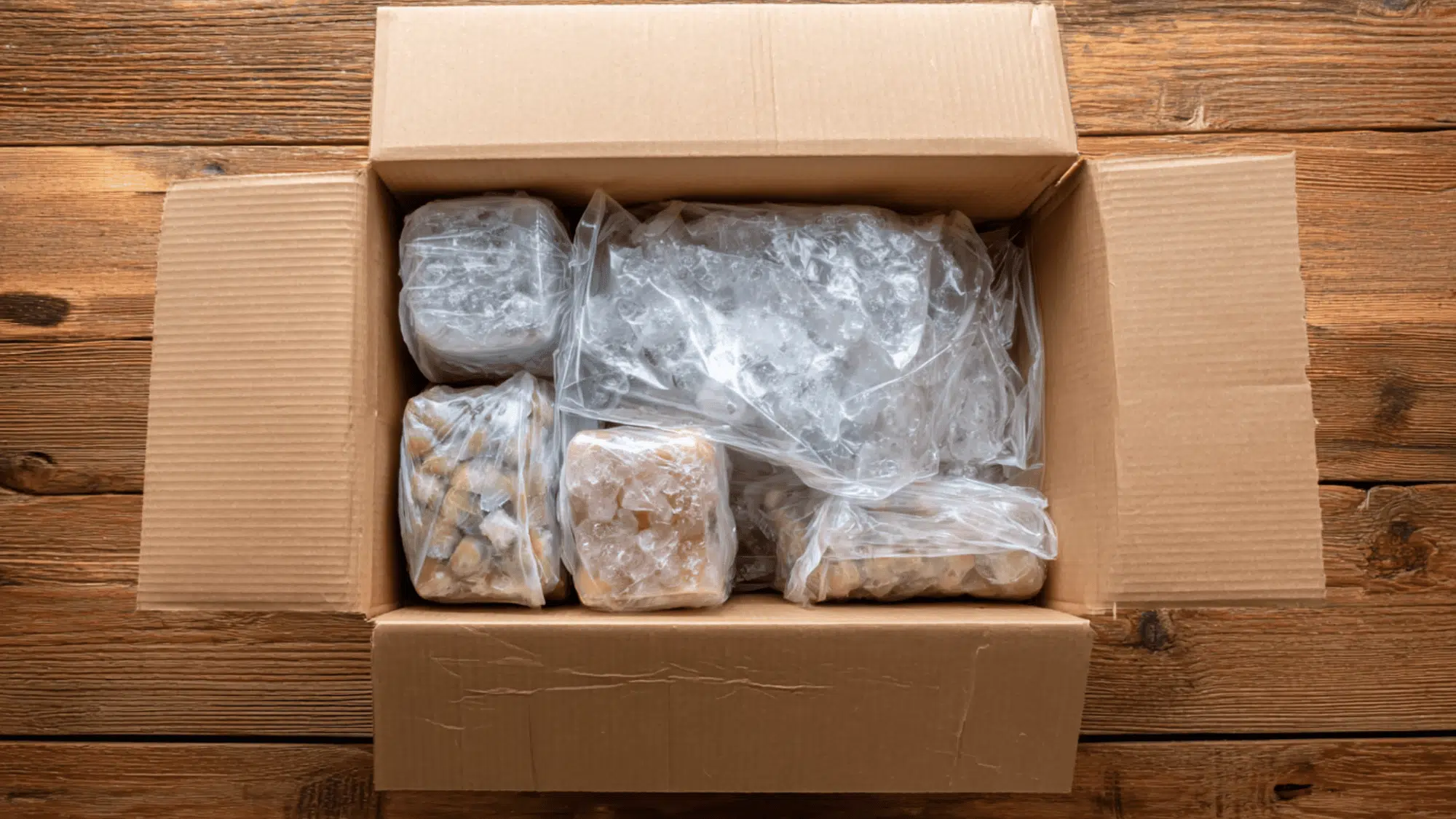 cardboard box filled with packaged food containers for shipping on wooden table