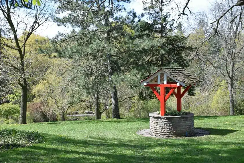 Stone wishing well with red wooden roof in a lush green park