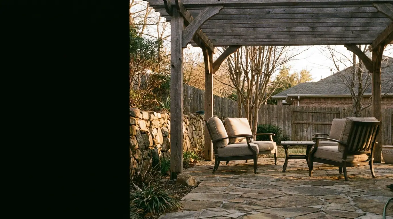 Outdoor patio with cushioned chairs under wooden pergola in a garden setting