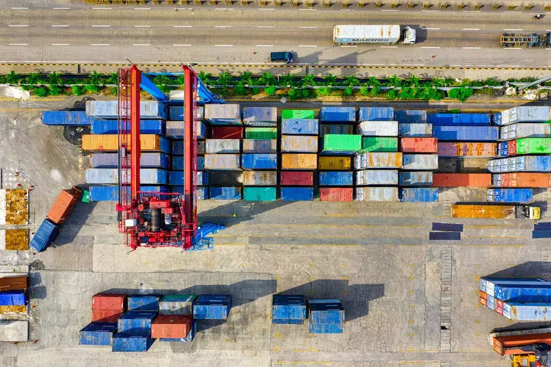 Aerial view of colorful shipping containers and crane at port terminal adjacent to highway