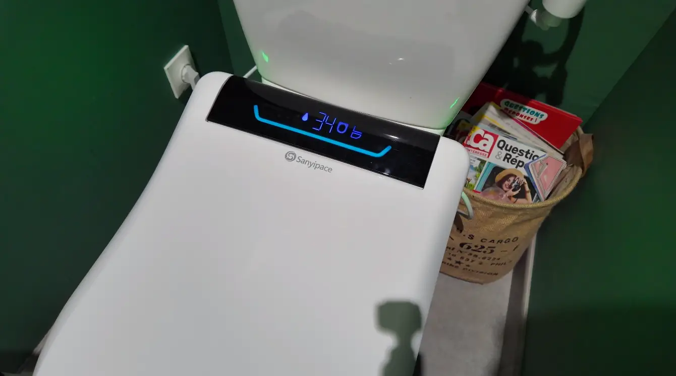 Smart toilet with digital display next to a basket holding magazines in a bathroom setting
