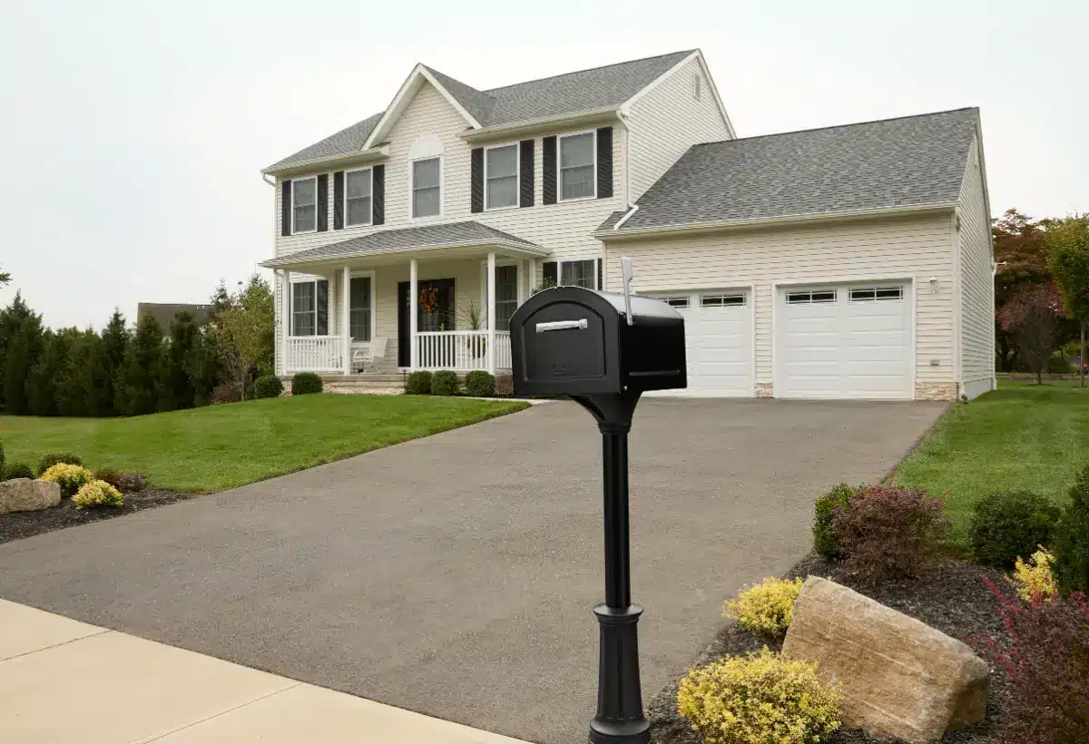 Two-story suburban house with front porch, black mailbox, and landscaped lawn in daylight