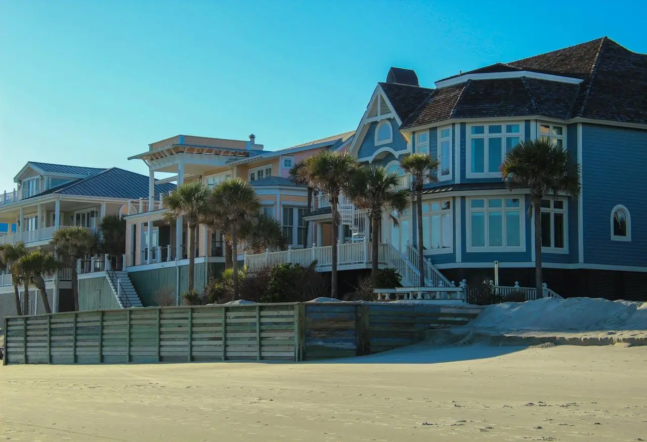 Coastal beachfront houses with palm trees under clear blue sky