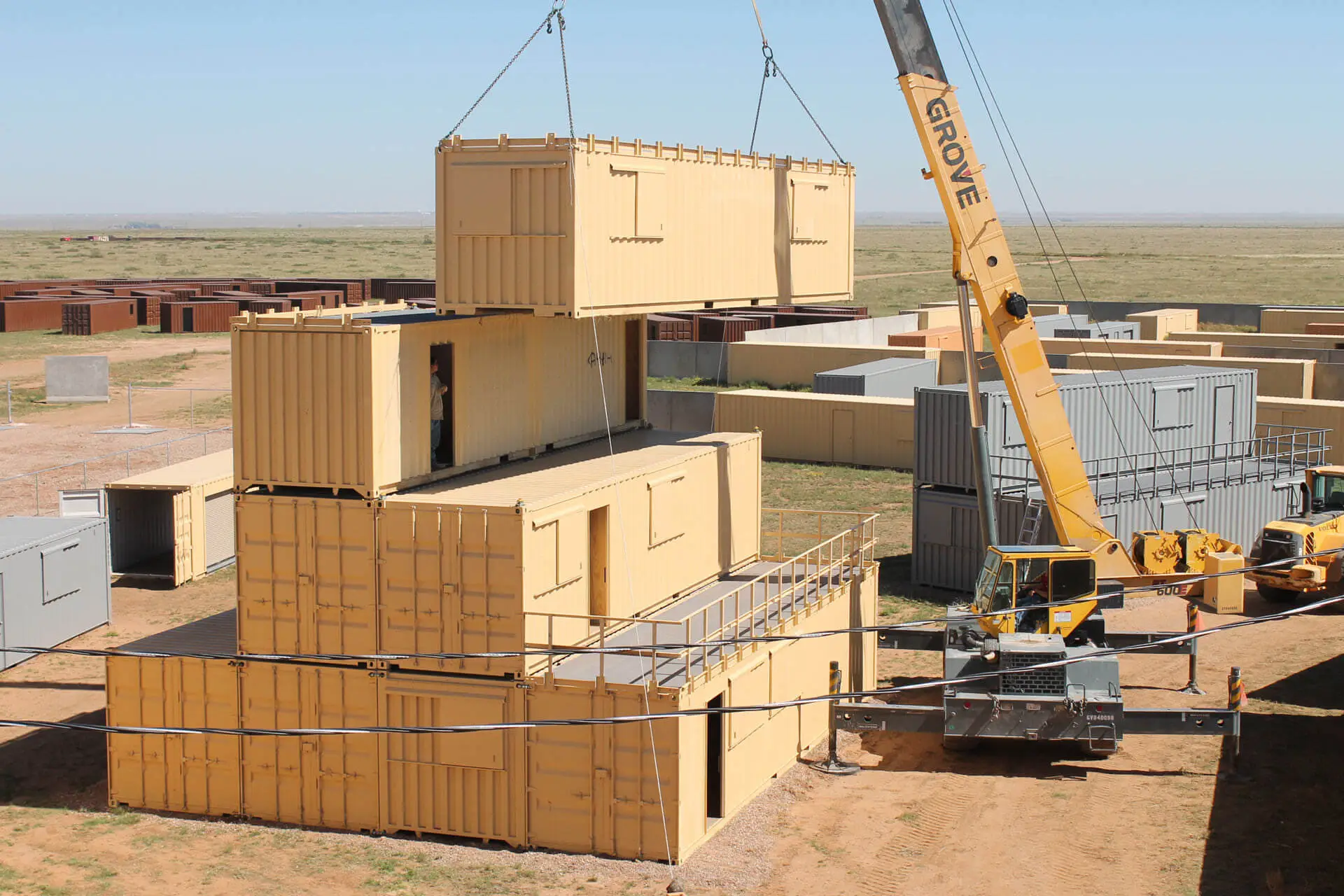 Crane stacking yellow shipping containers in an outdoor construction site