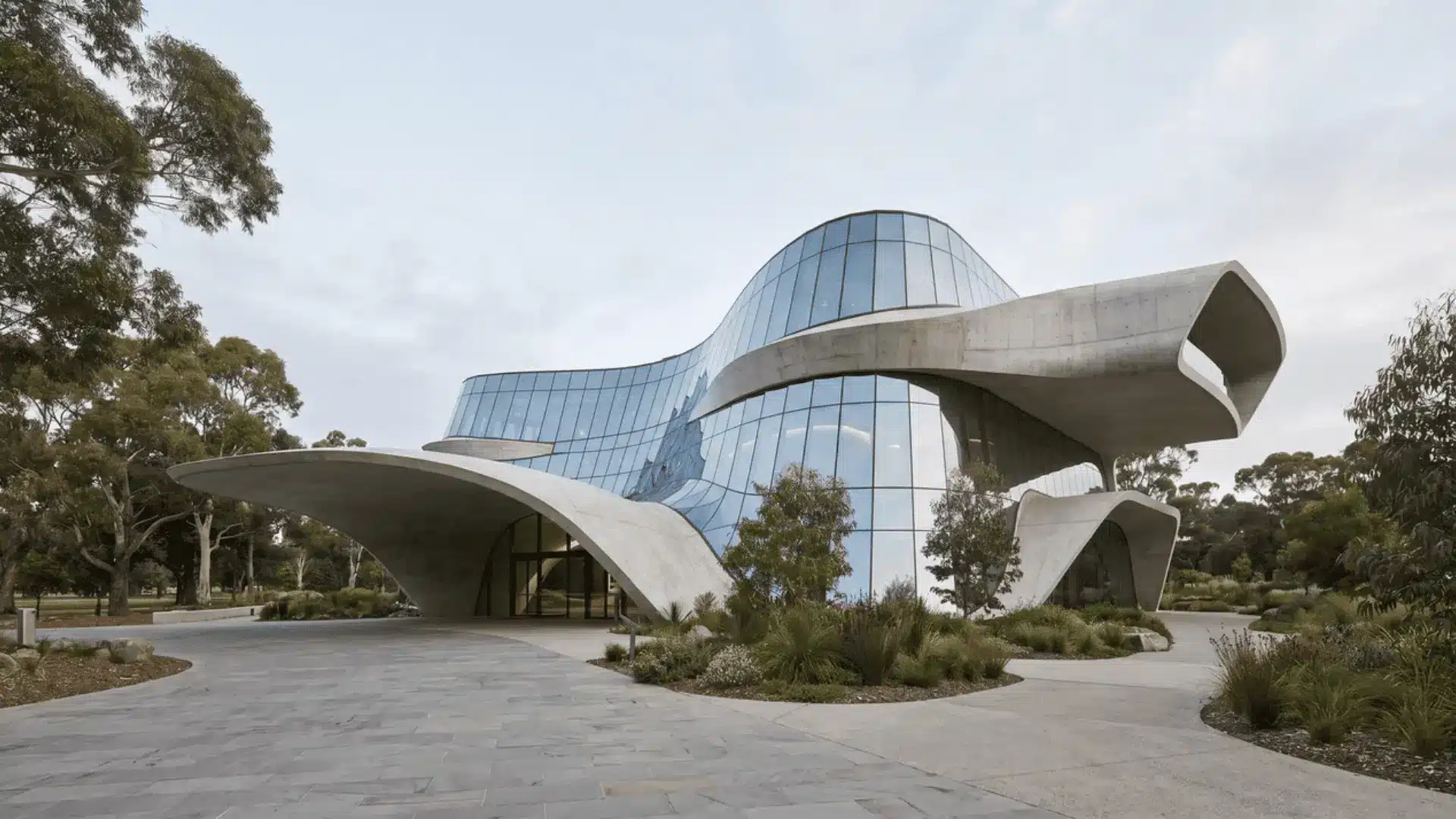 A futuristic modern building with glass facades and curved concrete structures, surrounded by greenery.