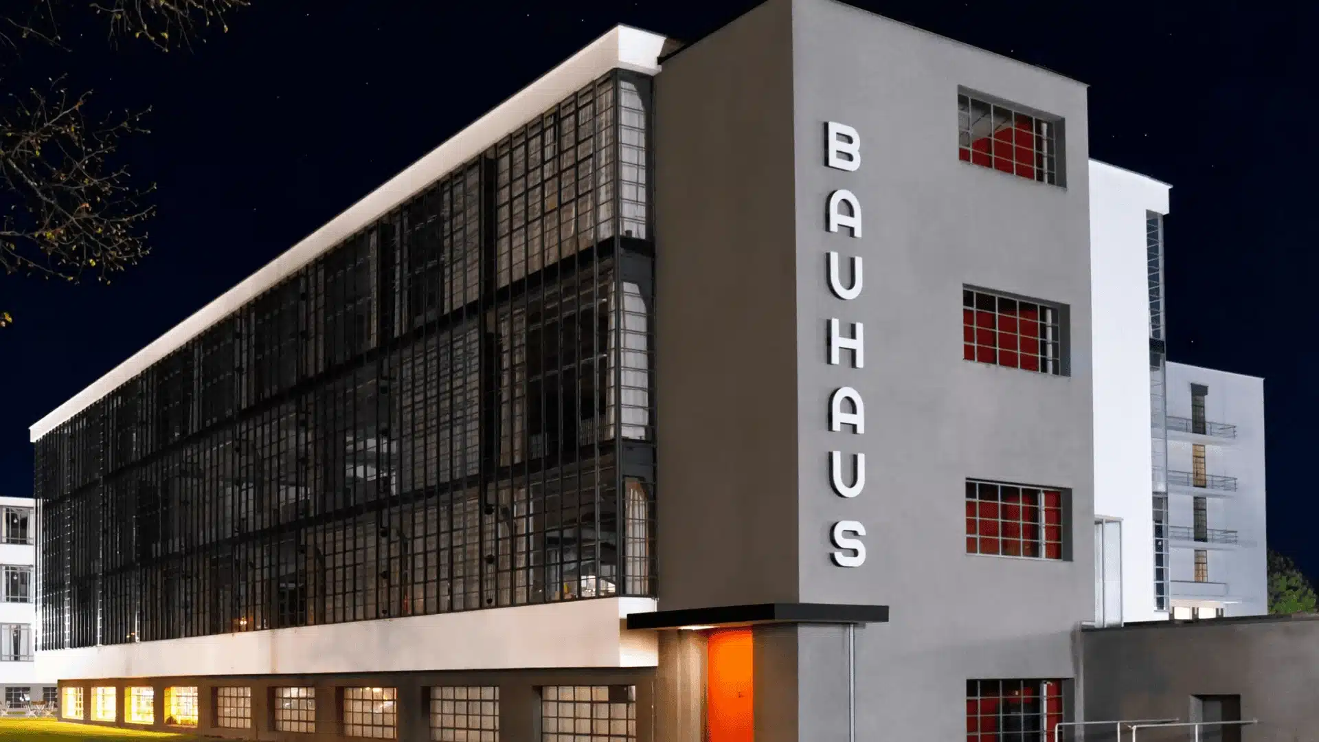 Bauhaus Dessau building at night, featuring minimalist design and illuminated BAUHAUS lettering.