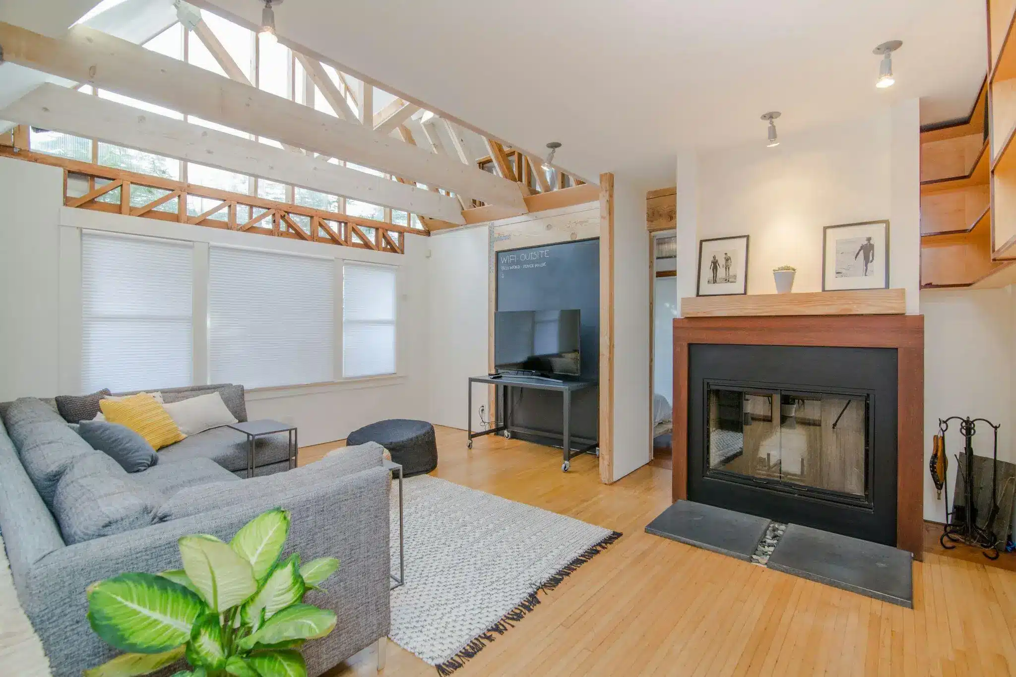 Modern living room with gray sectional sofa, indoor plant, and large fireplace under natural light