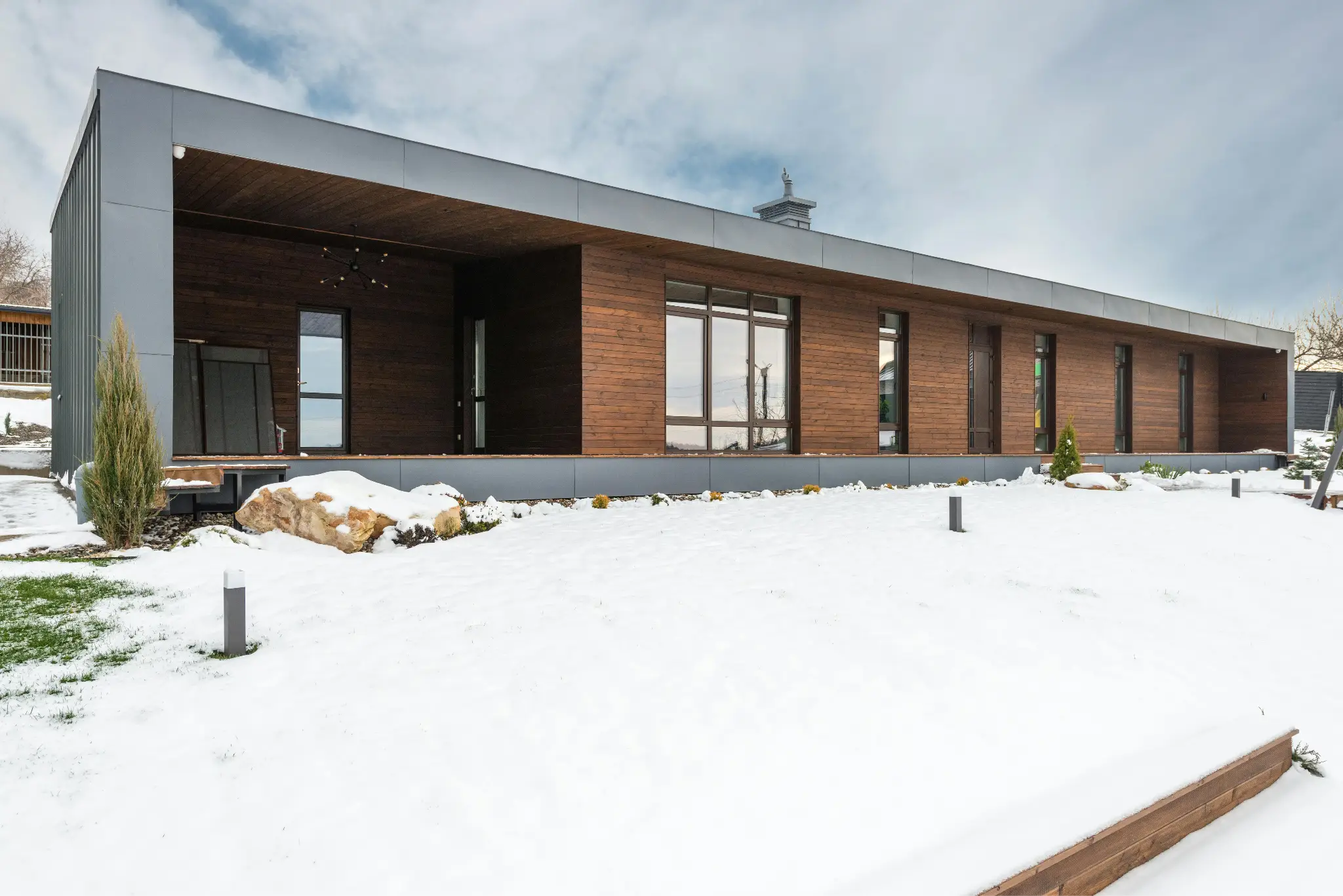 Modern wooden house with large windows in snowy outdoor setting