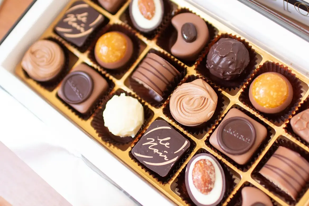 Assorted chocolates in a gold-lined box with various designs and textures