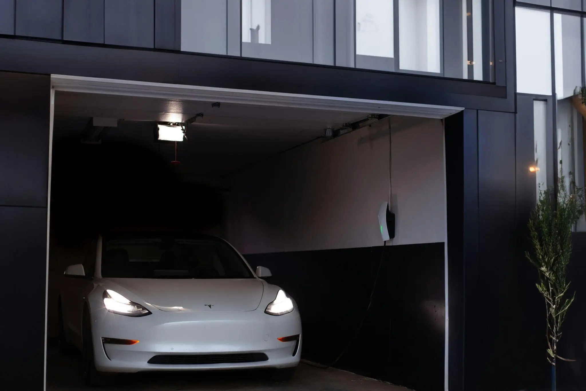 White electric car charging in a modern garage with wall-mounted charger
