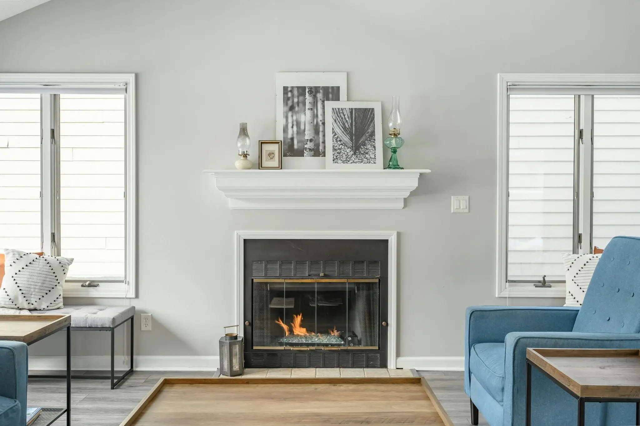 Fireplace with decorative mantel in modern living room featuring blue chairs and natural light