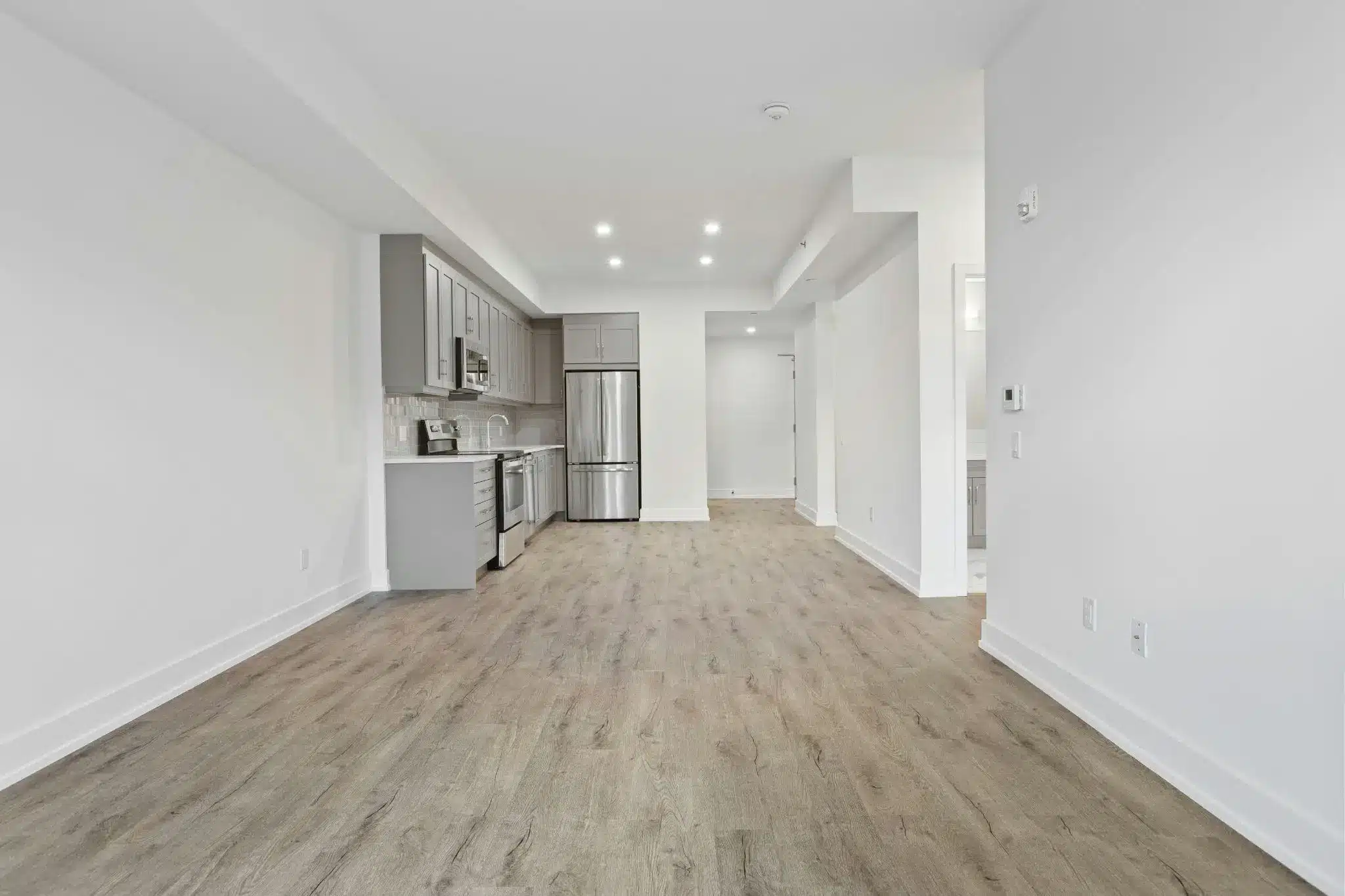 Modern kitchen with stainless steel appliances and gray cabinets in a bright, empty room