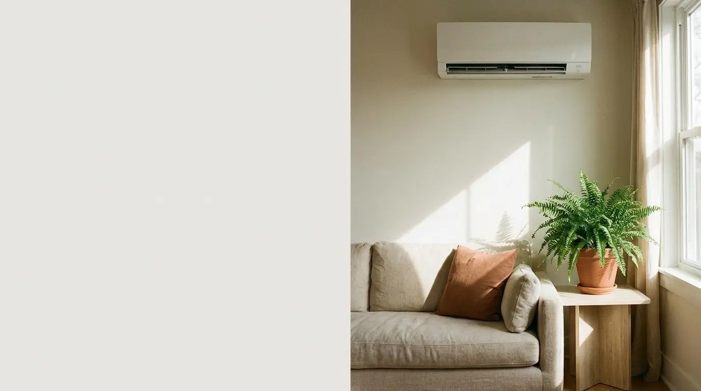 Beige sofa with rust cushion and potted fern under wall-mounted air conditioner in bright living room