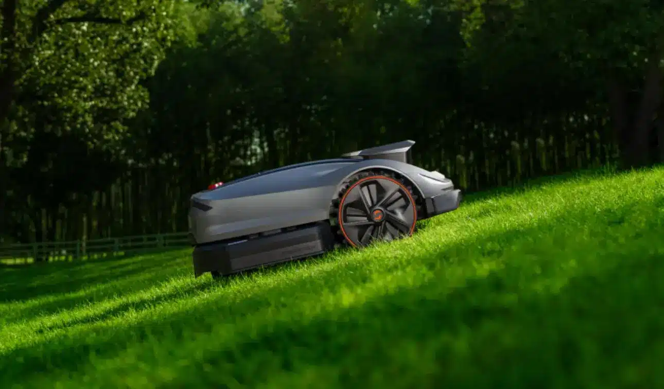 Robotic lawn mower on sloped grassy field in sunny garden setting