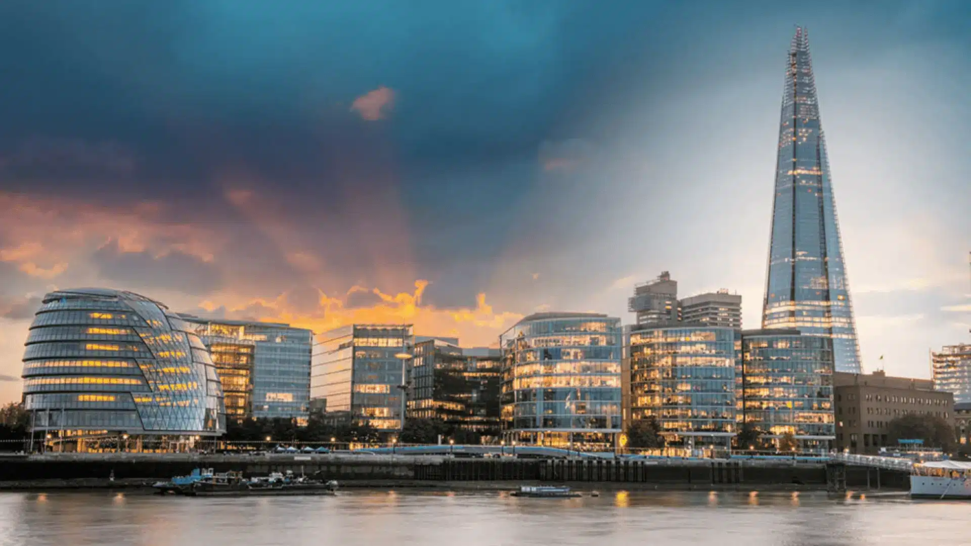 The Shard in London, towering above the city skyline with its sleek, glass exterior, illuminated against a dramatic sky at sunset.