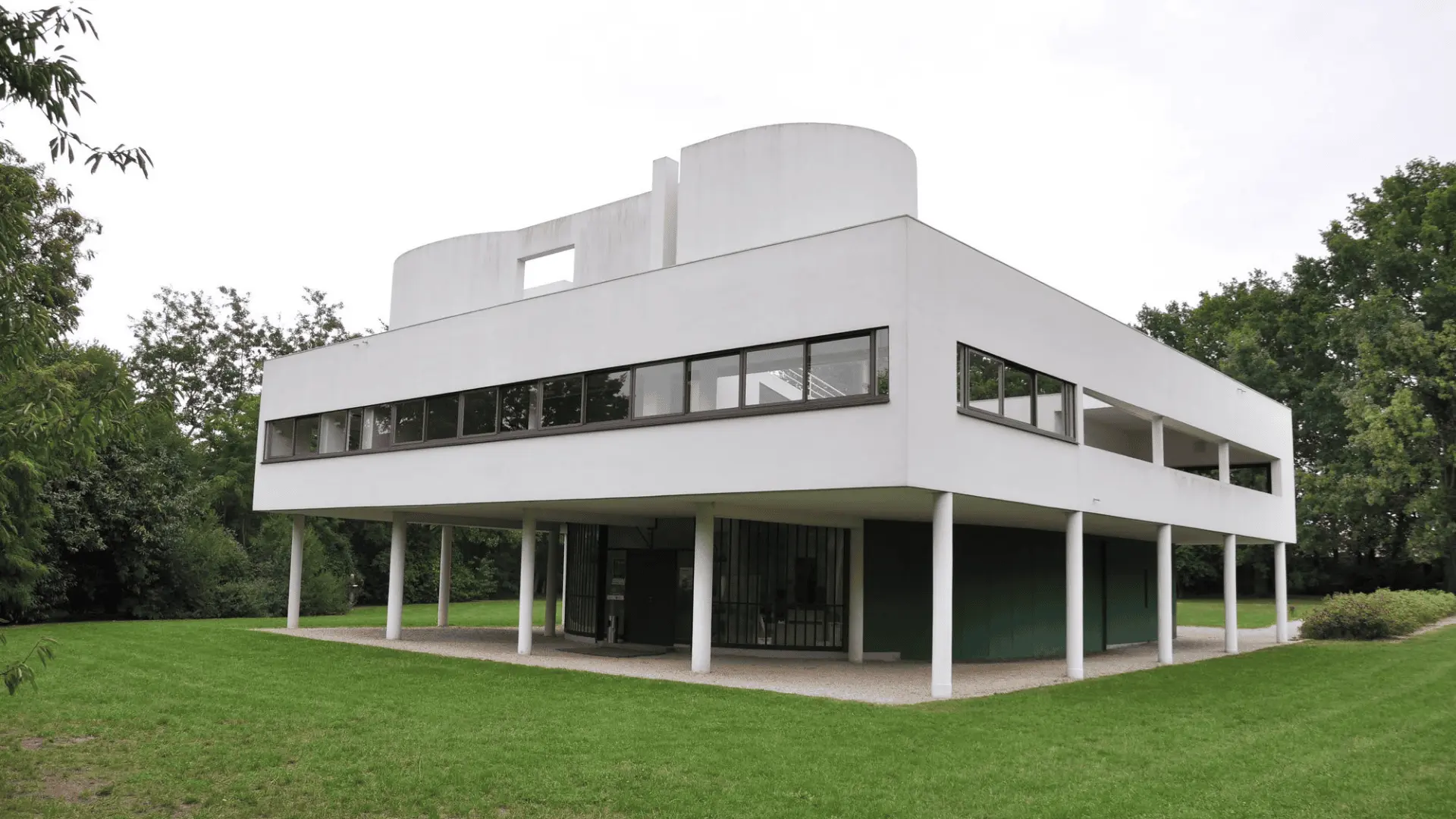 Villa Savoye, designed by Le Corbusier, a minimalist white structure on pilotis with large windows and a curved roof.