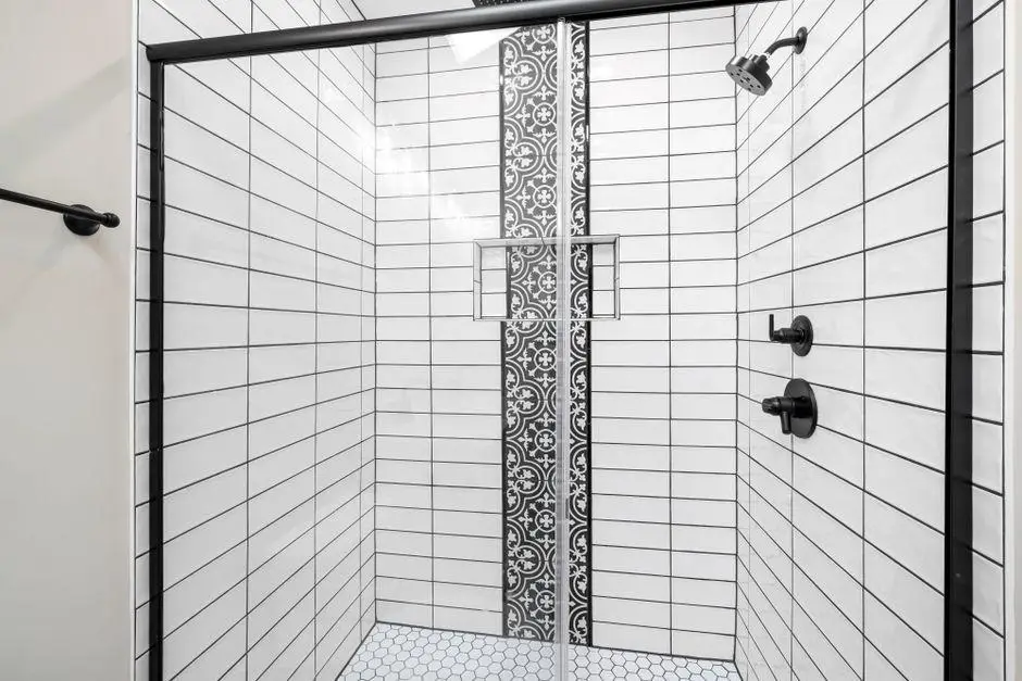 Black and white tiled shower with patterned accent strip and matte black fixtures