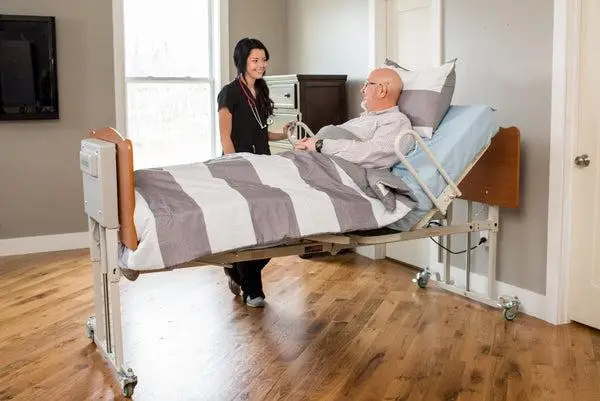 Nurse attending to patient in adjustable hospital bed in well-lit room