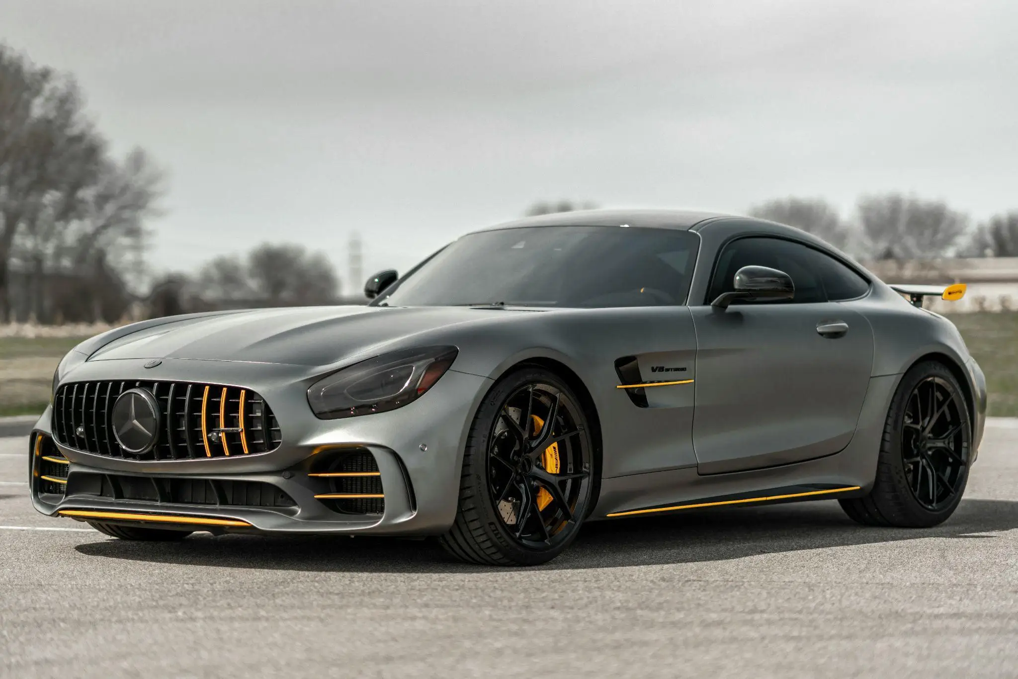 Sleek silver sports car with yellow accents parked on outdoor asphalt road