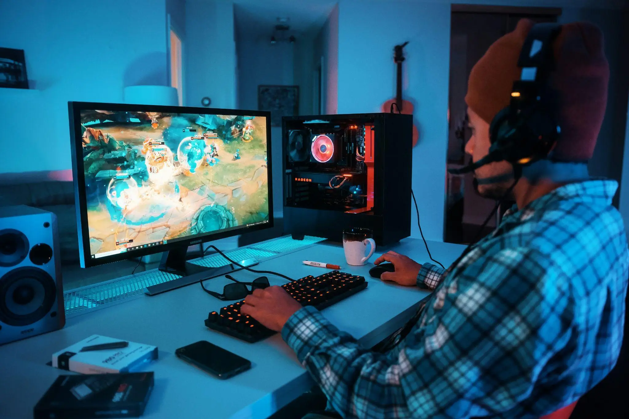 Gamer playing on desktop computer in dimly lit room with blue lighting and gaming peripherals