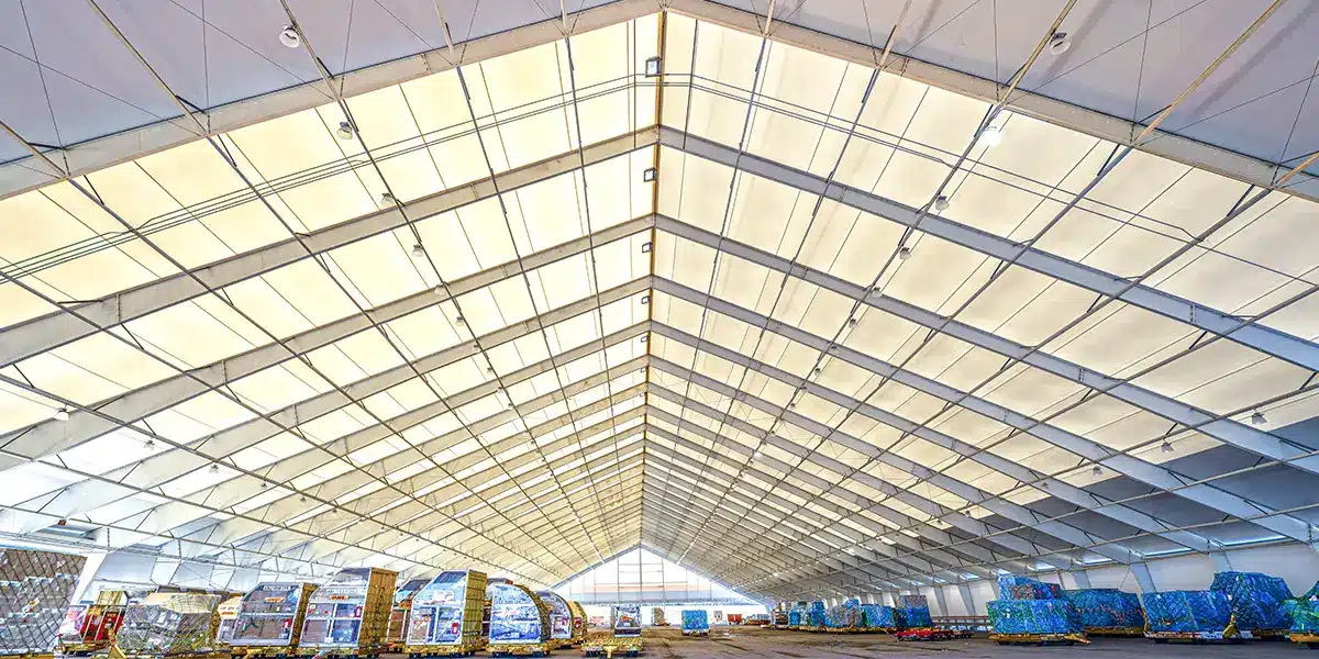 Large industrial warehouse interior with palletized goods under skylit ceiling