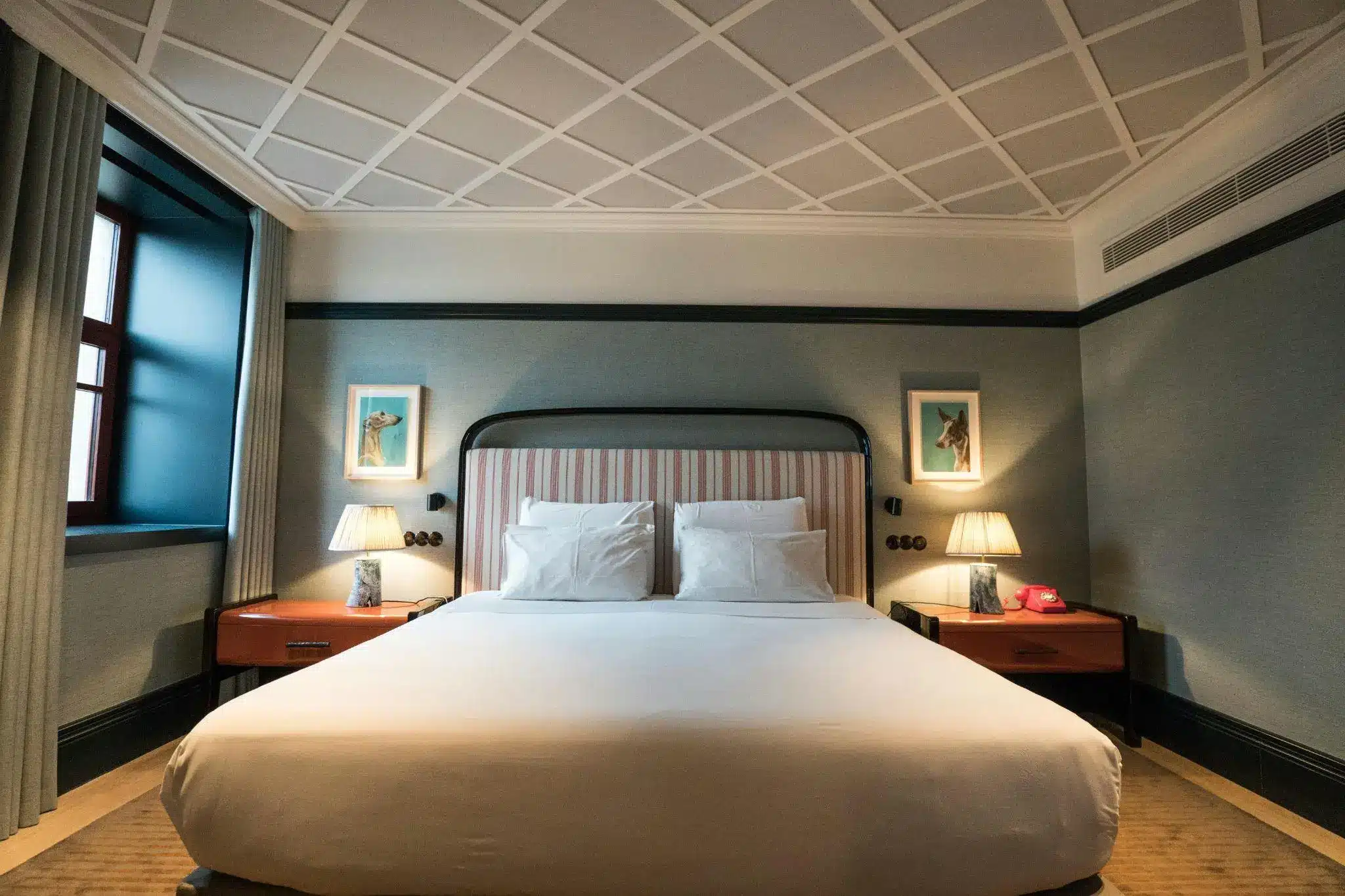 Elegant hotel room with striped headboard, bedside lamps, and framed animal prints