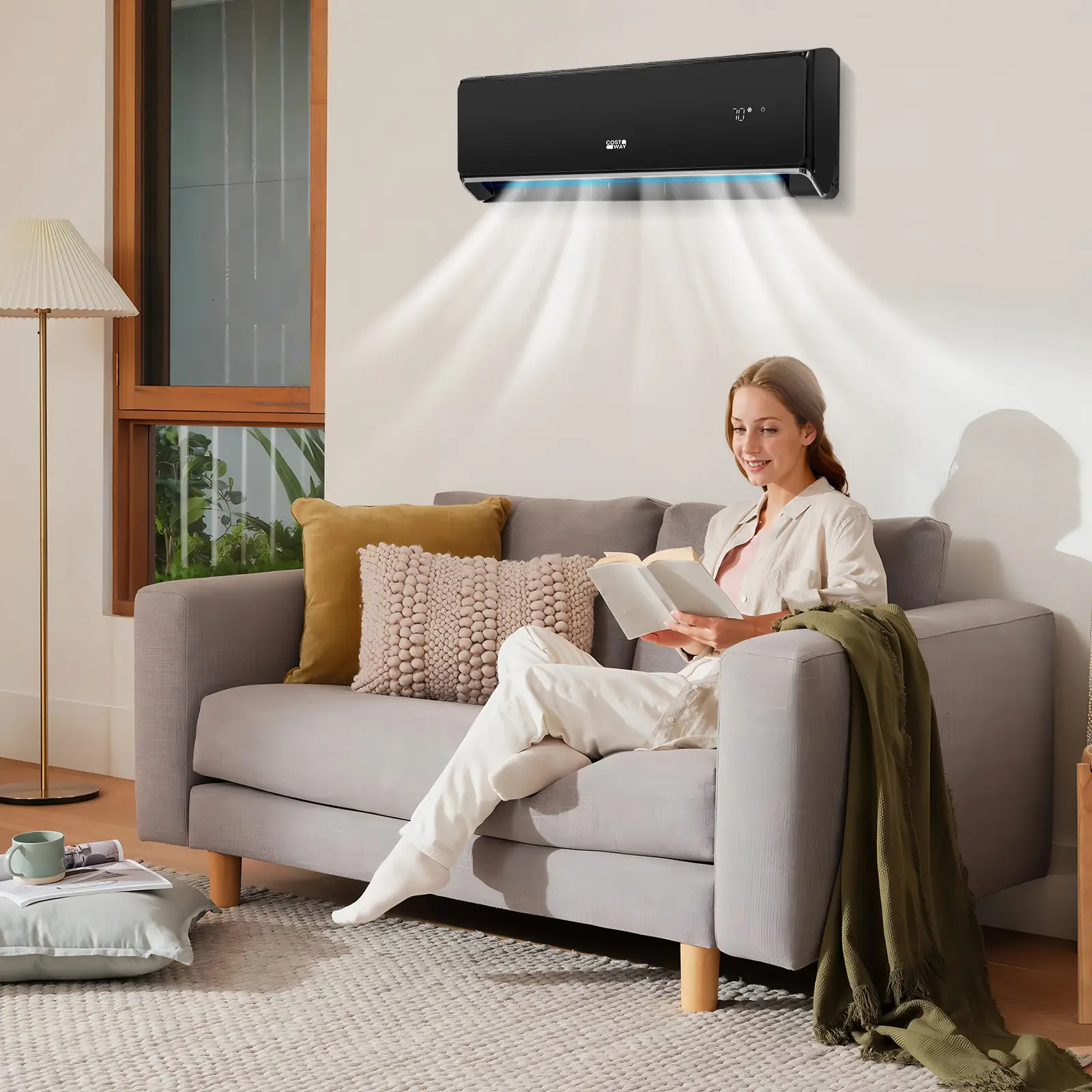 Woman reading on gray sofa under air conditioner in cozy living room