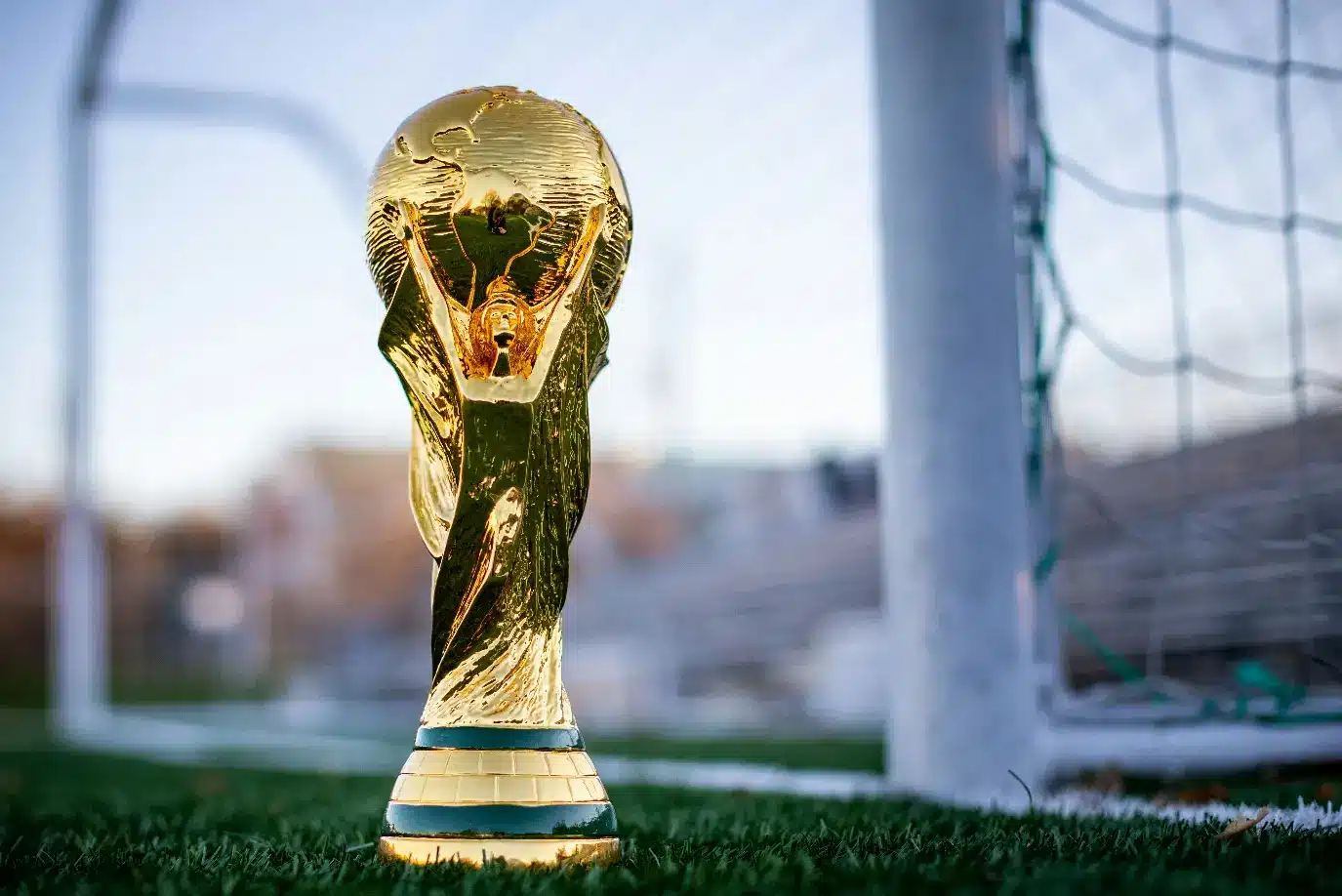 Golden trophy on a grassy soccer field in front of a goal net