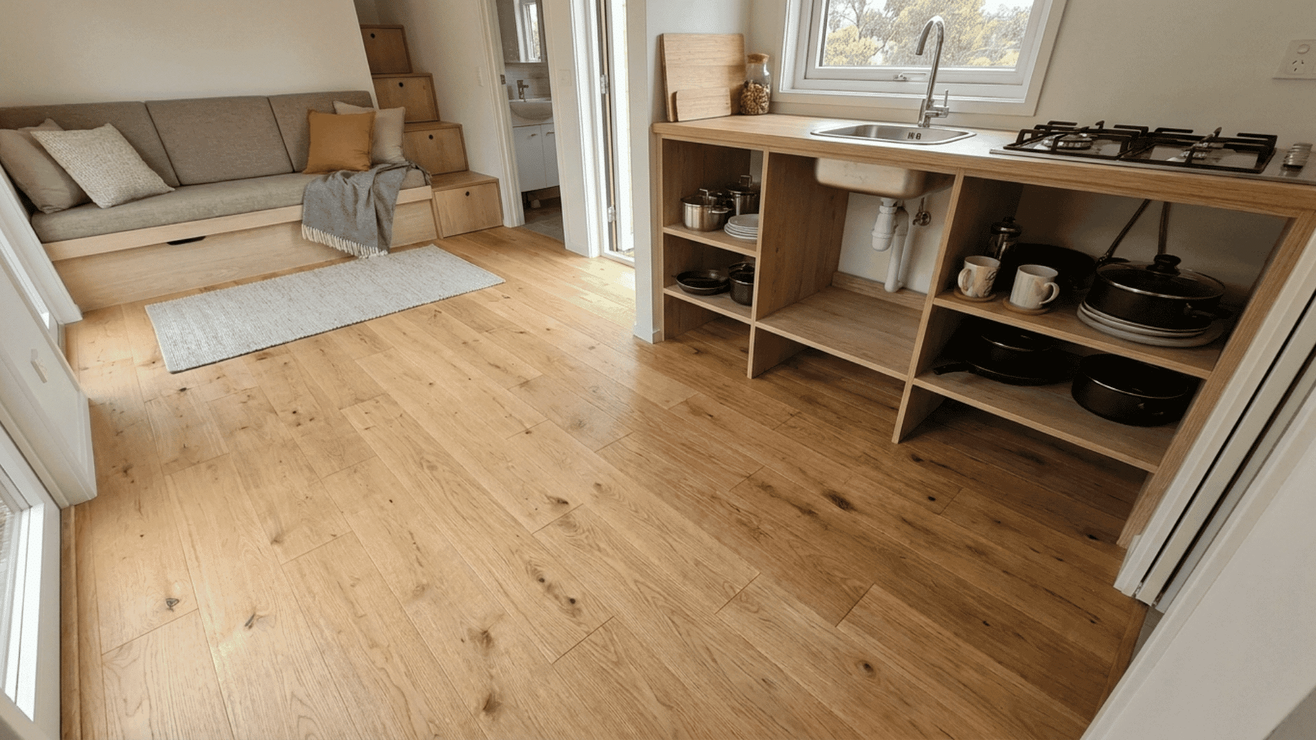 Tiny home interior with continuous flooring across living and kitchen areas