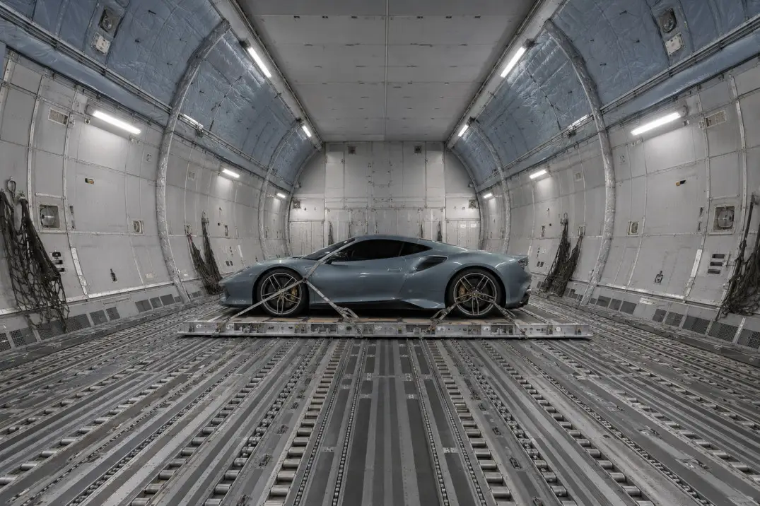 Sleek sports car secured inside metal cargo plane interior with dim lighting