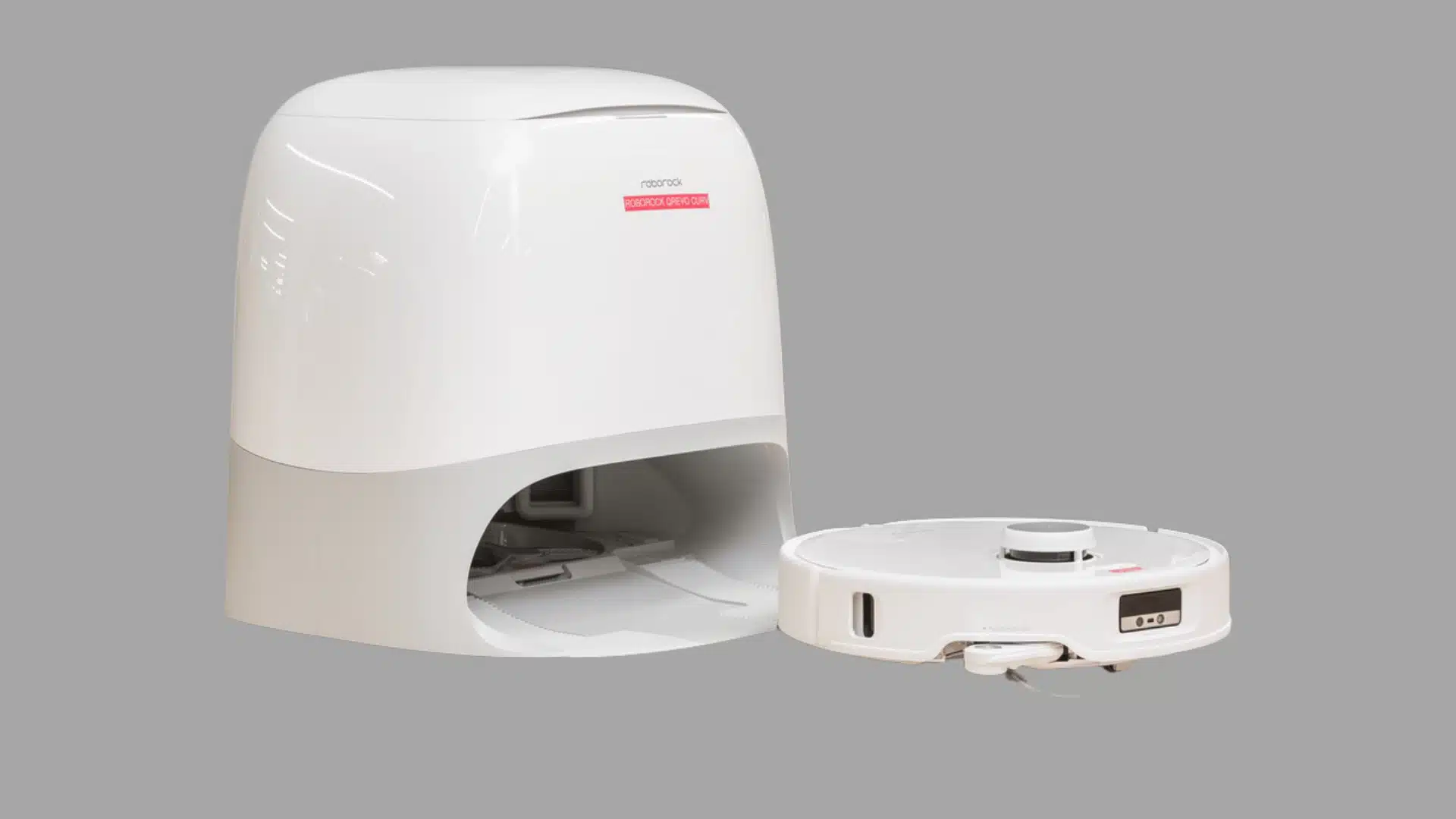 White robot vacuum with self-emptying dock placed on a table in a product testing workspace.