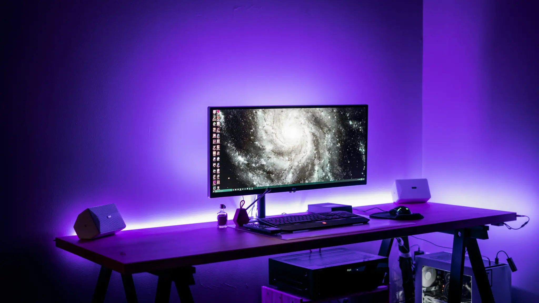 Ultrawide monitor on wooden desk with purple LED lighting in a dark room