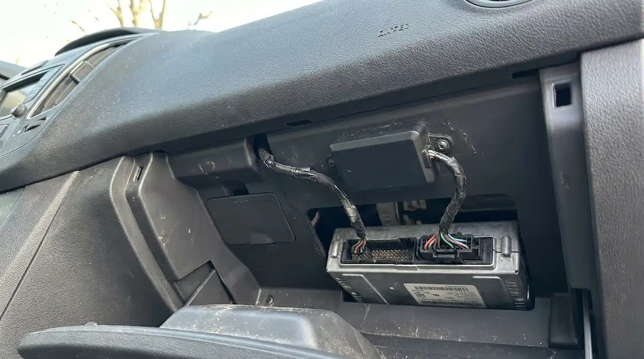 Telematics device mounted on a vehicle dashboard panel connected to a data interface module