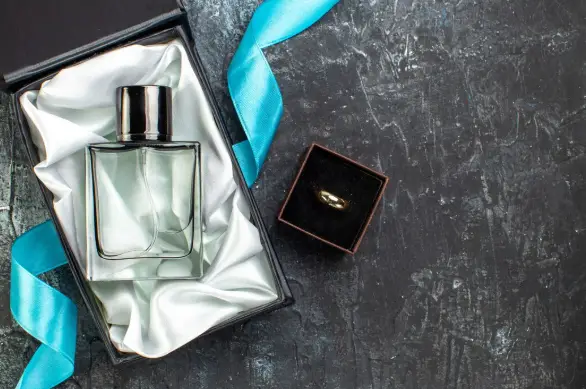 Perfume bottle in satin-lined box with blue ribbon on dark textured surface