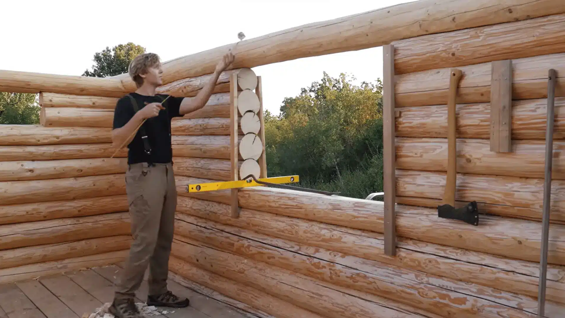 Measuring and marking a large window opening in the log cabin wall before cutting it to its final size